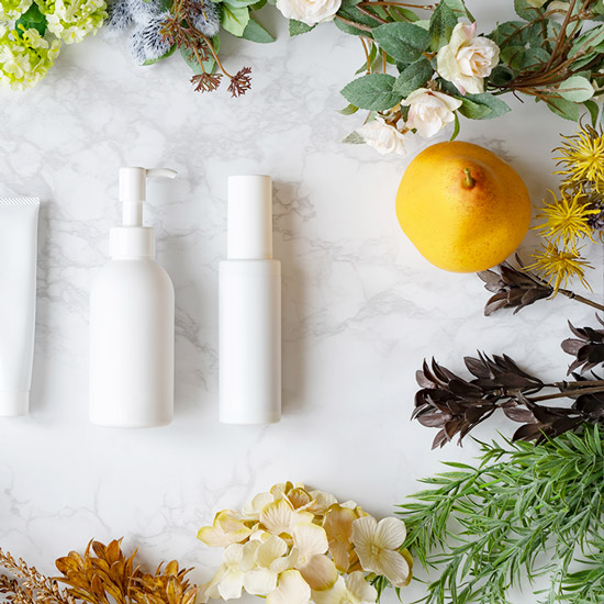 Naturkosmetik Weisse Flaschen neben Naturelementen