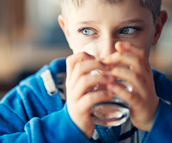 Denkbar einfache Anwendung dank Pulverform Kind hält ein Glas Wasser in der Hand