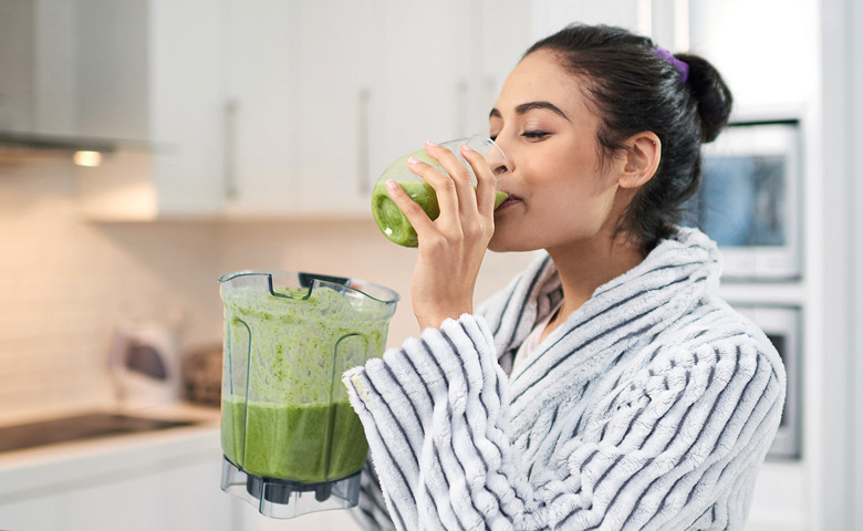 Frau trinkt grünen Smoothies