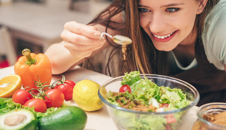 Junge Frau gibt Öl über ihren Salat