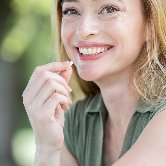 Woman smiling and taking a magnesium capsule