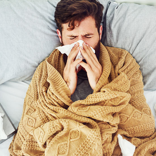 Vitamin C für das Immunsystem Mann mit Schnupfen im Bett