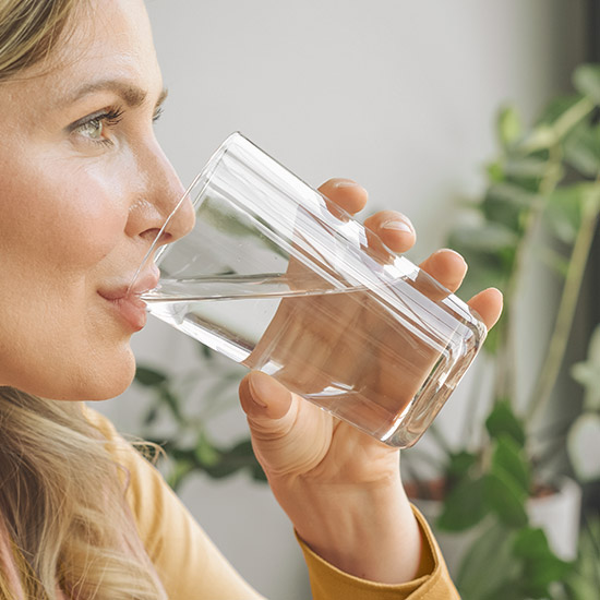 Frau trinkt Wasser mit Selen Tropfen drin