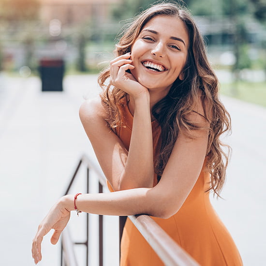 Glückliche Frau in orangem Kleid