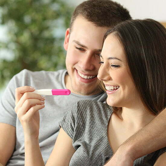 Pärchen schaut glücklich auf einen Schwangerschaftstest