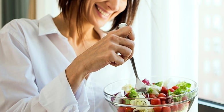 Eine Frau isst Salat. Kopfsalat enthält Folsäure.
