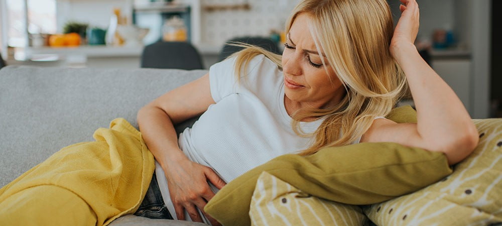 Frau hält sich Bauch vor Bauchschmerzen