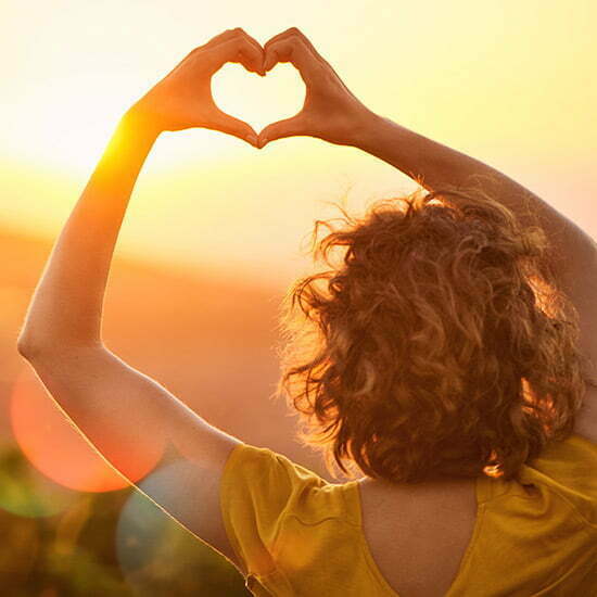 Vitamin D Synthese dank Sonne Frau stellt in der Sonne ein Herz mit ihren Händen dar