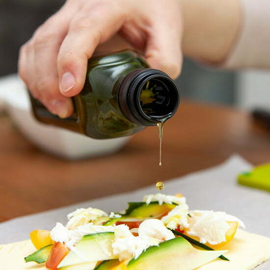 Olivenöl wird über ein Gericht gegossen.