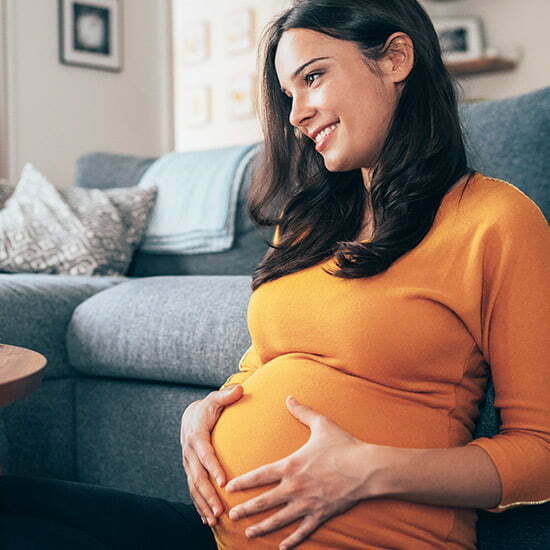 Schwangere Frau hält sich den Bauch.
