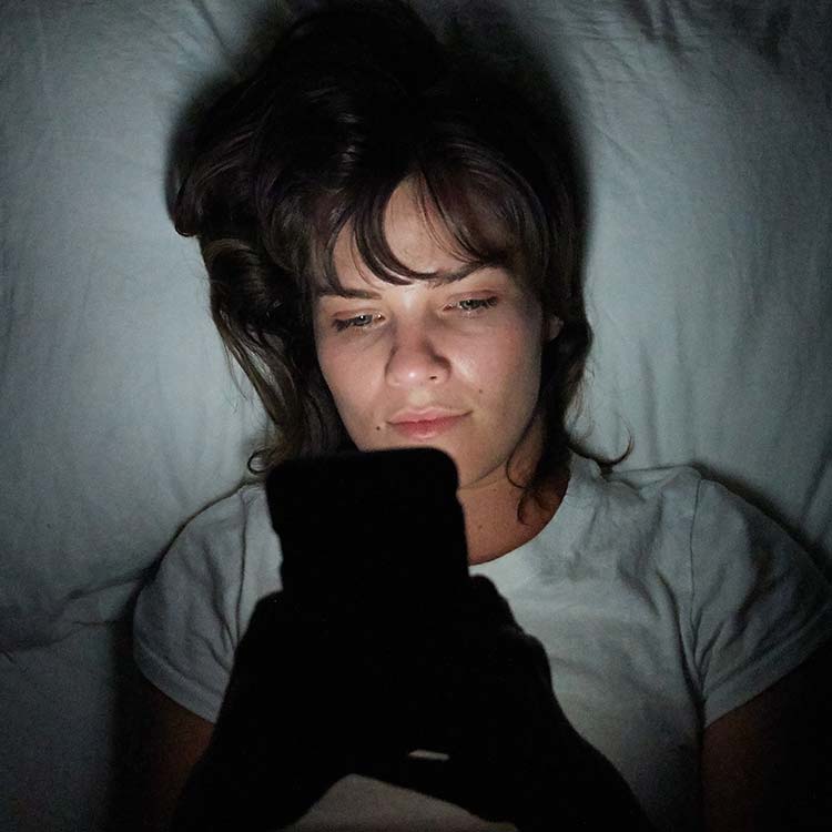 Frau benutzt Ihr Handy im Bett